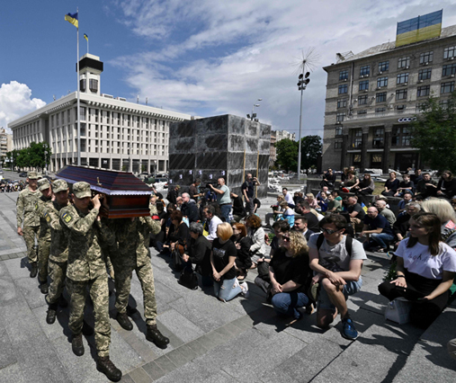 People knee as Ukrainian soldiers carry the coffin during the funeral ceremony for Ukrainian serviceman Roman Ratushny in Kyiv on Saturday (AFP photo)