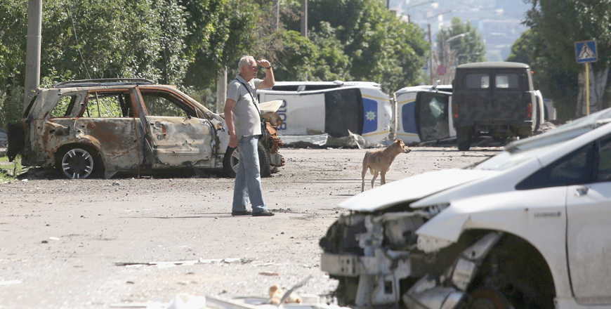 A man stands by a barricade made with destroyed police cars in Lysychansk on Tuesday, as Ukraine says Russian shelling has caused ‘catastrophic destruction’ in the eastern industrial city, which lies just across a river from Severodonetsk where Russian and Ukrainian troops have been locked in battle for weeks (AFP photo)