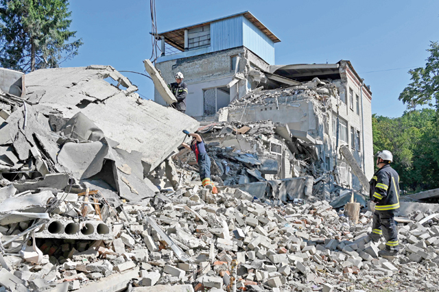 Rescuers work in the wreckages of a destroyed school after being hit by a rocket in Kharkiv on Monday (AFP photo)
