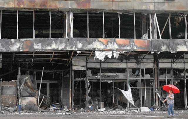 A woman carries an umbrella as she walks past a destroyed shopping mall in Bucha, Kyiv region, on Tuesday, amid Russia's invasion of Ukraine (AFP photo)