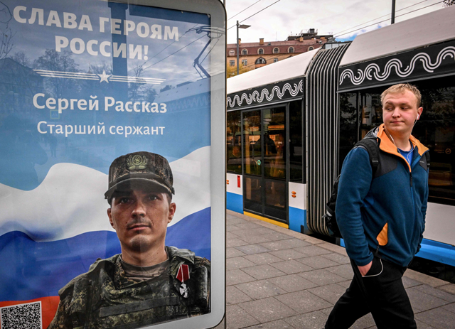 A pedestrian walks past a billboard displaying a Russian soldier with a slogan reading 'Glory to the Heroes of Russia' decorating a bus stop in central Moscow on Wednesday (AFP photo)