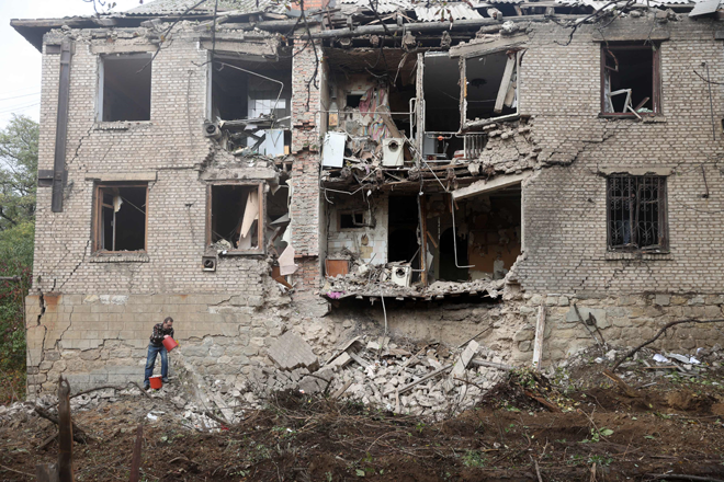 A local resident clean debris next to a residential building destroyed by a missile strike in Konstantinovka in the eastern Donetsk region on Friday (AFP photo)