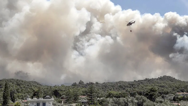 A firefighting helicopter flies over the the village of Alepochori, after an overnight fire on a mountain range overlooking the Gulf of Corinth, on May 20, 2021 (AFP photo)