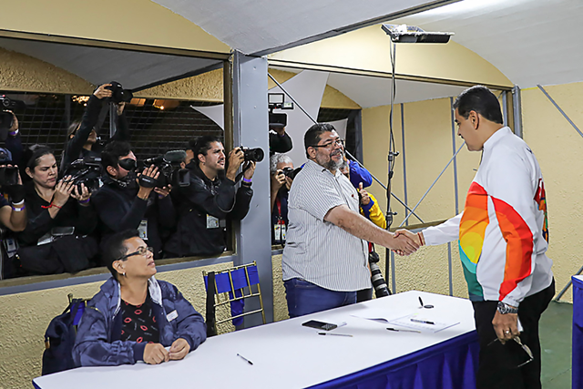 Handout photo released by the Venezuelan Presidency showing Venezuela’s President Nicolas Maduro (right) shaking hands with a member of the National Electoral Council during a consultative referendum on Venezuelan sovereignty over the Essequibo region controlled by neighbouring Guyana, in Caracas on Sunday (AFP photo)