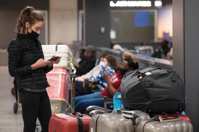 A woman stands among a large collection of luggage as she uses her phone at Dulles International Airport in Dulles, Virginia, on Monday (AFP photo)