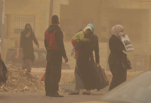 Pedestrians are met with dusty conditions in Amman on Thursday (Photo by Osama Aqarbeh)
