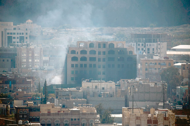 Smoke billows behind a building in the Yemeni capital Sanaa on Sunday, during clashes between Houthi rebels and supporters of Yemeni ex-president Ali Abdullah Saleh (AFP photo)