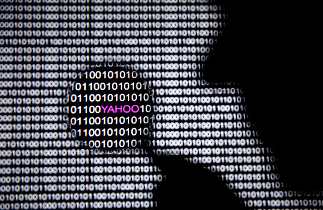 A photo illustration shows a man in front of a Yahoo logo seen through a magnifying glass in front of a displayed cyber code on December 16 (Reuters photo)