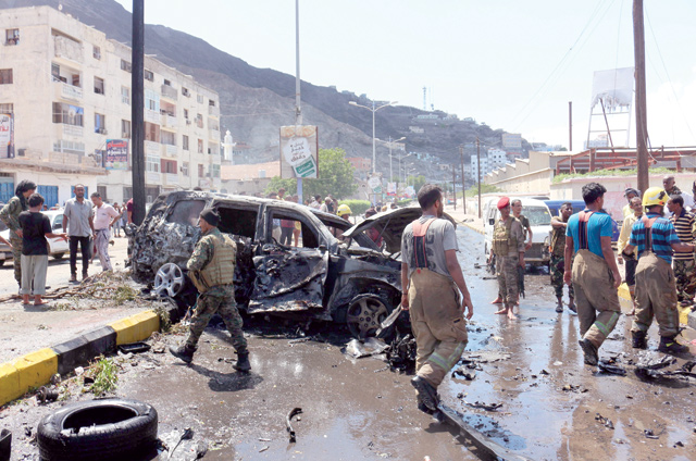 Yemeni security forces and rescue teams gather around the carcass of a burnt car following an explosion that hit Yemen's southern port city of Aden on Sunday (AFP photo)
