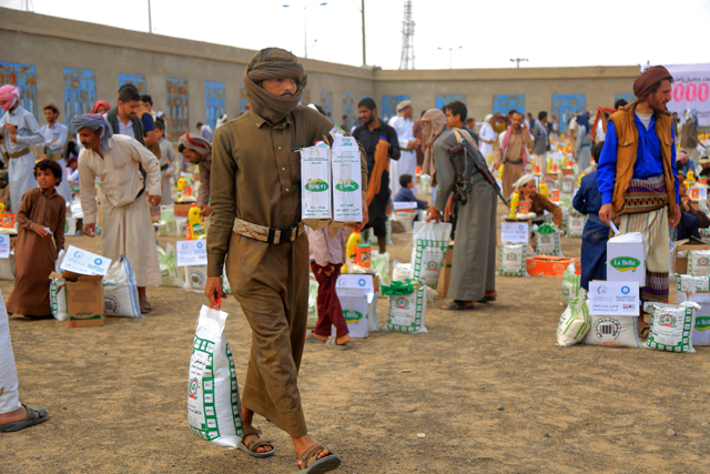 In this photo taken on Thursday, men carry humanitarian aid provided by a Kuwaiti charitable organisation during a distribution to displaced Yemenis on the outskirts of the north-eastern city of Marib (AFP photo)