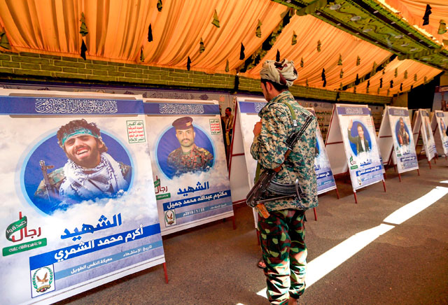 A Houthi rebel fighter looks at portraits of comrades who were reportedly killed in action while fighting against Yemeni forces of the Saudi-led coalition-backed government, on display during an exhibition marking ‘Martyrs' Day’, in the Houthi-controlled Yemeni capital of Sanaa on Tuesday (AFP photo)