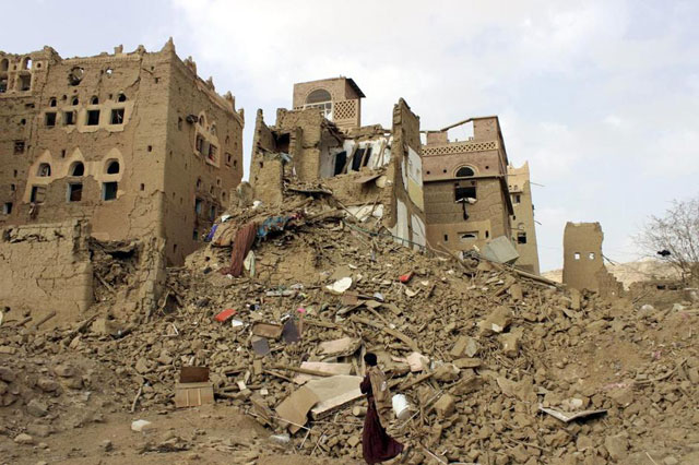 A man walks past houses damaged by Saudi-led air strikes in Yemen's northwestern city of Saada on May 26, 2015 (Reuters photo)