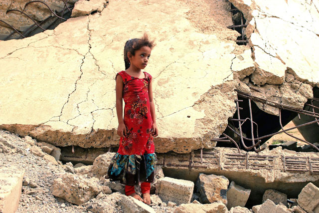 A Yemeni girl who was displaced with her family, stands amidst the rubble of a building that was destroyed at an unknown date, in the district of Abs in Yemen's north-western Hajjah province, on Saturday (AFP photo)