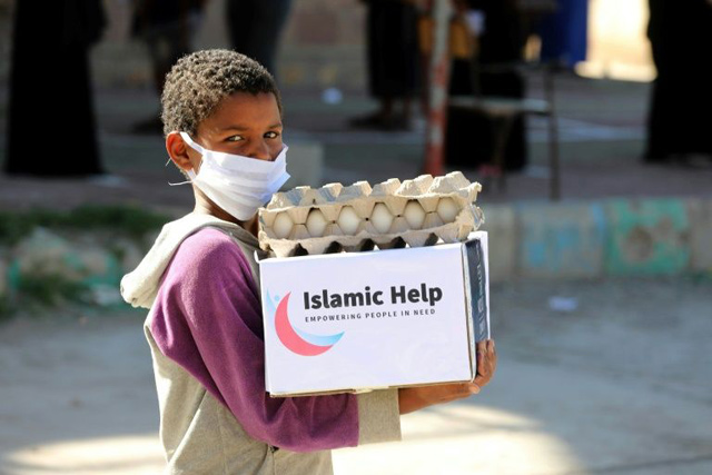 A child wearing a protective mask receives humanitarian aid in Yemen's third city of Taez, on May 8, amid the coronavirus pandemic (AFP photo)