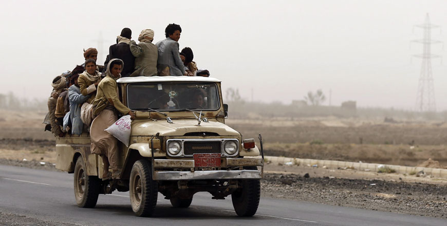 People ride on the back of a pickup truck on the outskirts of Yemen's capital Sanaa on Thursday.Fuel shortages in Yemen have caused hikes in taxi fees, forcing many to use vans and pickup vehicles as taxis (Reuters photo)