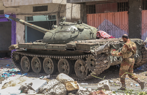 A Yemeni fighter loyal to the country’s exiled president walks past a tank on a road in the southwestern city of Taez on Monday (AFP photo)