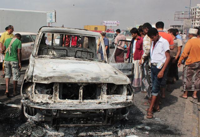 Yemenis look at the wreckage of a vehicle on Tuesday in the aftermath of clashes between forces loyal to Saudi-backed President Abed Rabbo Mansour Hadi and Al Qaeda militants in the Mansura suburb of Aden (AFP photo)