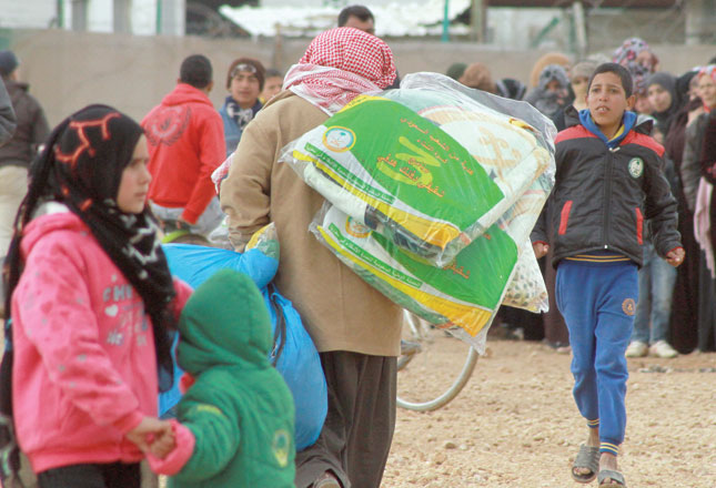 A Syrian refugee carries blankets and supplies at the Zaatari Refugee Camp, some 90km northeast of Amman, in January (Photo by Hassan Tamimi)