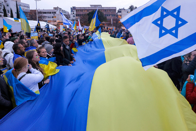 Demonstrators wave a giant flag of Ukraine alongside other smaller flags of Ukraine and Israel during a protest against Russia's invasion of Ukraine and ahead of a televised address by the Ukrainian president in Israel's Mediterranean coastal city of Tel Aviv, on Sunday (AFP photo)