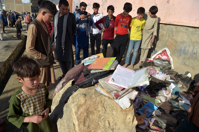 Onlookers stand next to the backpacks and books of victims following Saturday’s multiple blasts outside a girls' school in Dasht-e-Barchi on the outskirts of Kabul Sunday, as the death toll has risen to 50, the interior ministry said (AFP photo)