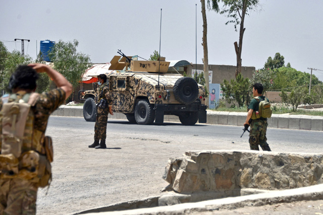 Afghan security personnel stand guard along the road amid ongoing fight between Afghan security forces and Taliban fighters in Kandahar, on Friday (AFP photo)