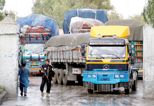 An Afghan security guard stands while supply trucks carrying containers for export line at the customhouse in Jalalabad, Afghanistan, May 14 (Reuters photo)
