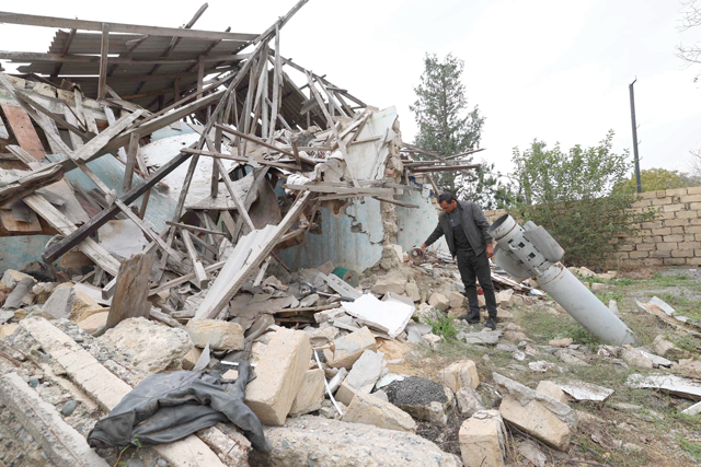 Javid Ismayilov picks up a teapot from the debris, next to a missile in the ground, and in front of his house destroyed during the 2020 war between Azerbaijan and Armenian separatists, in the town of Terter, on Sunday (AFP photo)