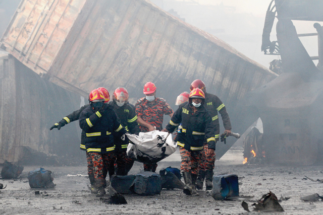 Firefighters carry the dead body of a victim from the site after a fire broke out at a container storage facility in Sitakunda, about 40km from the key port of Chittagong, on Sunday (AFP photo)