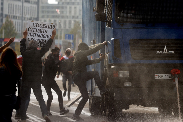 Protesters try to stop a water cannon truck during a rally demanding to free jailed activists of the opposition in Minsk on Saturday (AFP photo)