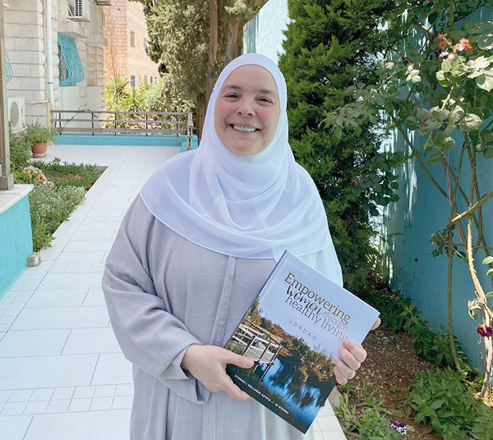 Woman carries a copy of Empowering Women through Healthy Living – Jordan, a book showcasing women success stories (Jt photo)