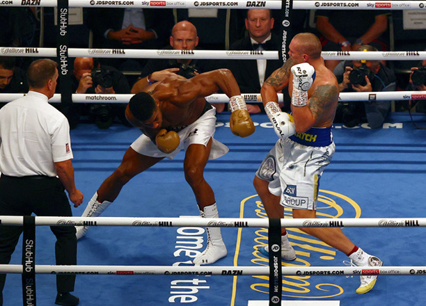 British heavyweight champion boxer Anthony Joshua (centre) and Ukrainian boxer Oleksandr Usyk (right) exchange punches during their heavyweight boxing match in London on Saturday (AFP photo by Adrian Dennis)