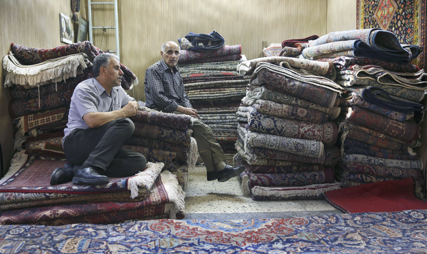 In this August 10, photo, Iranian merchants wait for customers at a carpet shop in Tehran's old, main bazaar, Iran (AP photo)