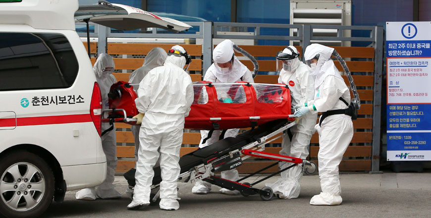 Medical workers wearing protective gear carry a patient infected with the COVID-19 coronavirus at a hospital in Chuncheon on Saturday (AFP photo)