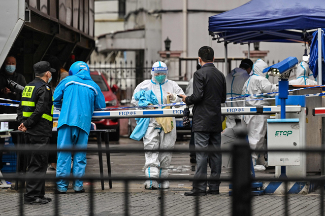 A delivery man (left in blue) is seen arriving to deliver an order outside of a locked down neighbourhood after the detection of new cases of COVID-19 in Huangpu district, in Shanghai, on Thursday (AFP photo)