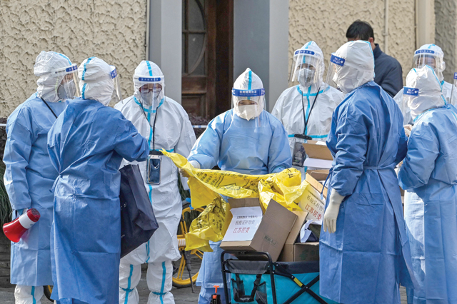 Health workers wearing protective gear prepare equipment before testing people for the COVID-19 coronavirus at a residential compound in Shanghai on Wednesday (AFP photo)