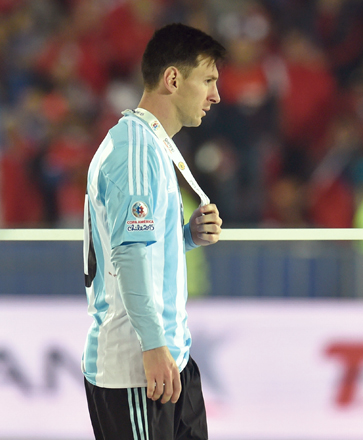 Argentina’s forward Lionel Messi walks with the second place medal of the 2015 Copa America championship in Santiago on Saturday (AFP photo by Rodrigo Arangua)