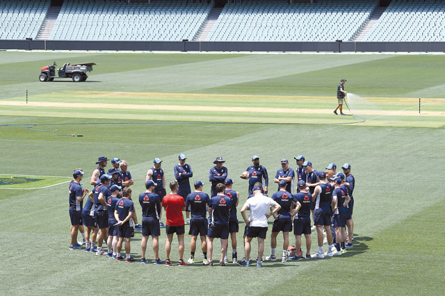 A groundsman sprays water on the pitch as England cricket team players and coaching staff stand in a circle during a training session at the Adelaide Oval in Australia on Thursday (Reuters photo)
