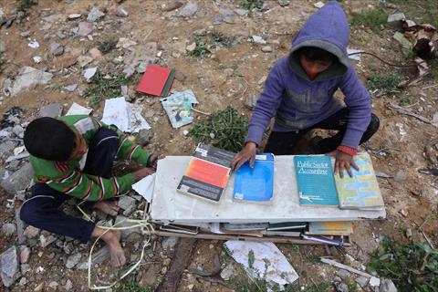 Displaced Palestinians collect books, from the destroyed Islamic University to use as fuel to cook food, in Gaza City on March 21, 2025 (AFP photo)