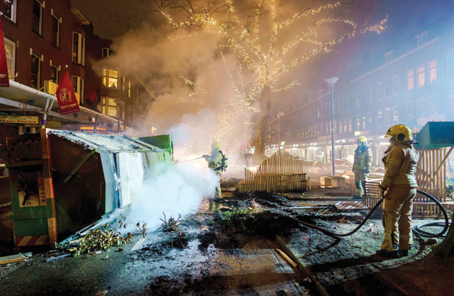 Firefighters work to extinguish a fire on the Groene Hilledijk in Rotterdam, on Monday, after a second wave of riots in The Netherlands following the introduction of a coronavirus curfew over the weekend (AFP photo)