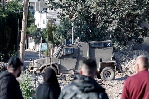 An Israeli military vehicle is parked outside the martyrs cemetery, while Palestinians try to visit the tombs of relatives as part of the ritual at the start of Eid Al Fitr in the Jenin refugee camp in the Israeli-occupied West Bank on March 30, 2025 (AFP photo)