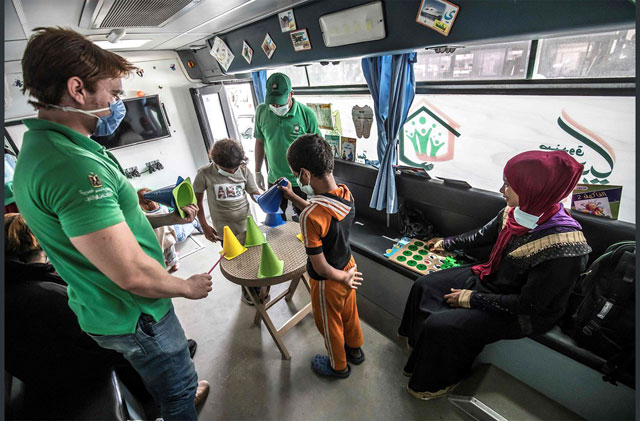 Social workers look on as children play an educational game inside one of the mobile units run by the Egyptian authorities (AFP photo)