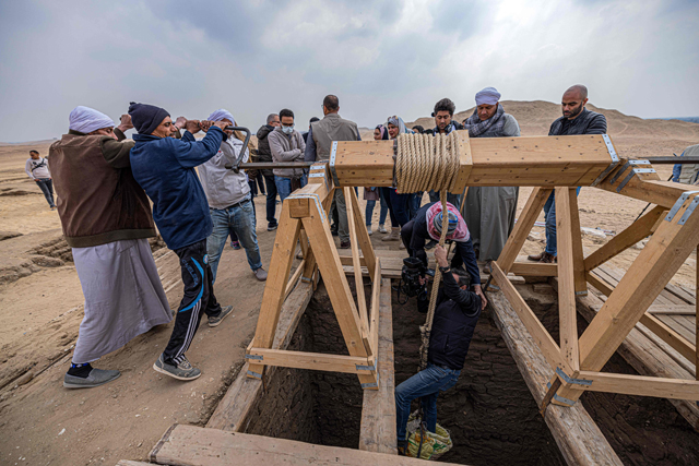 A member of the media is lowered on Saturday, into one of five ancient Pharaonic tombs, recently discovered at the Saqqara archaeological site, south of the Egyptian capital Cairo (AFP photo)