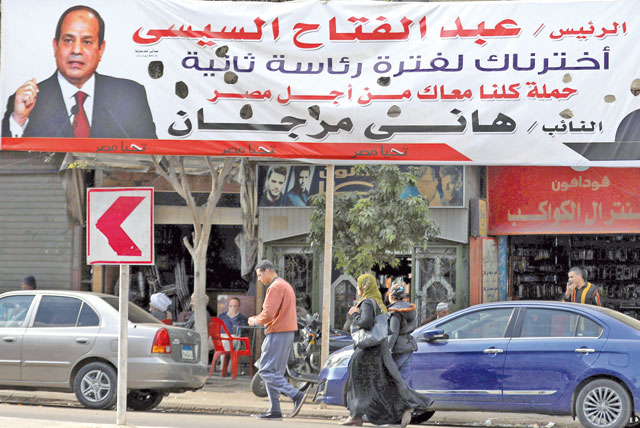 People walk near a poster depicting Egypt's President Abdel Fattah Al Sisi that reads ‘we've chosen you for a second term’, in Cairo, Egypt, on Monday (Reuters photo)