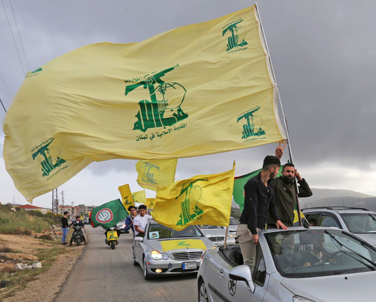 A supporter of Lebanon's Hizbollah, gestures as he holds a Hizbollah flag in Marjayoun, Lebanon, on Monday (Reuters photo)