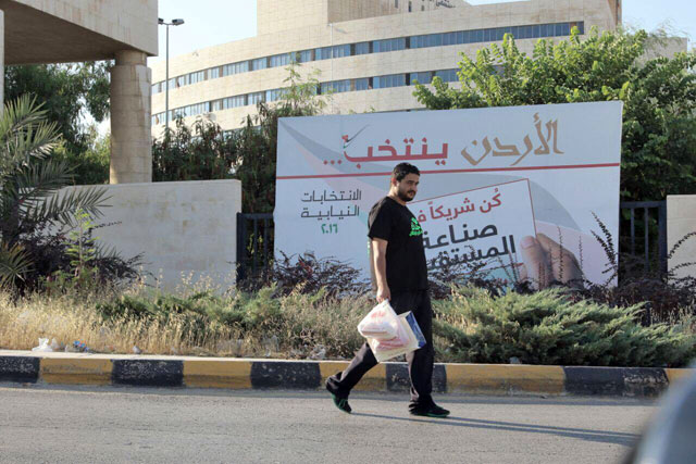 A man walks past a sign encouraging people to vote in the upcoming parliamentary elections slated for September 20  (Photo by Osama Aqarbeh)