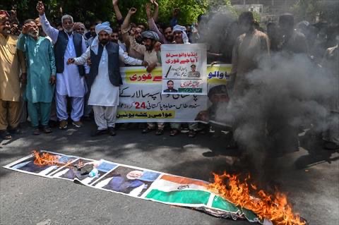Members of the Awami Rickshaw Union burn a banner with images of the Indian national flag and Prime Minister Narendra Modi during an anti-Indiaprotest in Lahore on April 27, 2025. Troops from Pakistan and India exchanged fire in disputed Kashmir for a third night in a row, officials said on April 27, as relations between the nuclear-armed rivals plunged to their lowest level in years (AFP photo)