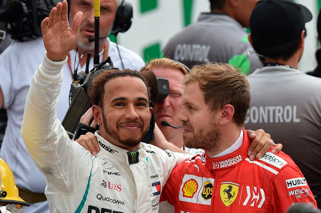Mercedes’ British driver Lewis Hamilton (left) waves at the crowd as he hugs Ferrari’s German driver Sebastian Vettel, after winning his fifth drivers’ title after the F1 Mexico Grand Prix in Mexico City on Sunday (AFP photo by Rodrigo Arangua)