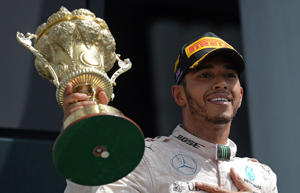 Mercedes AMG Petronas F1 Team’s British driver Lewis Hamilton lifts the trophy as he celebrates on the podium after the British Formula One Grand Prix at Silverstone motor racing circuit in Silverstone, England, on Sunday (AFP photo by Oli Scarff)