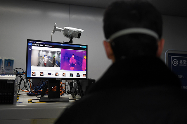 A security guard keeps watch as an AI-powered system developed by Chinese tech firm Megvii screens commuters for fevers as they enter the Mudanyuan metro station in Beijing, in undated photo (AFP photo by Greg Baker)