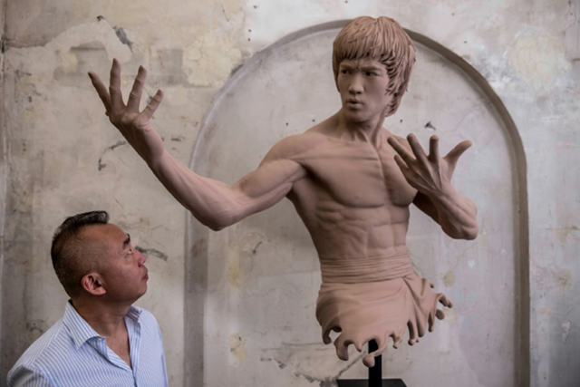 W. Wong, chairman of Hong Kong’s Bruce Lee Club, looks at a bust of his childhood hero at an exhibition marking the 50th anniversary of the martial arts legend’s death (AFP photo by Isaac Lawrence)